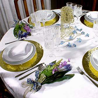 tavola natalizia con tovaglia bianca, fiori di seta spruzzati d'oro
